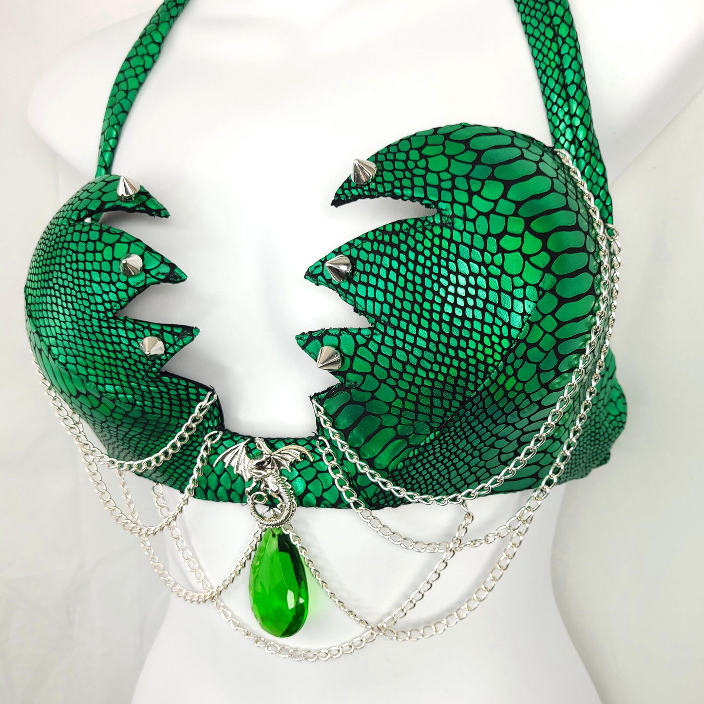 Green snake-like headdress with silver chains and a green pendant on a mannequin.